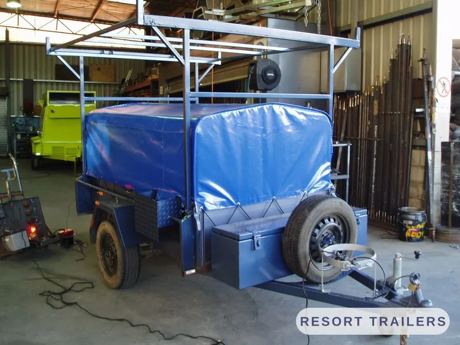 Canoe racks over a box trailer with a blue tonneau cover — built by Resort Trailers