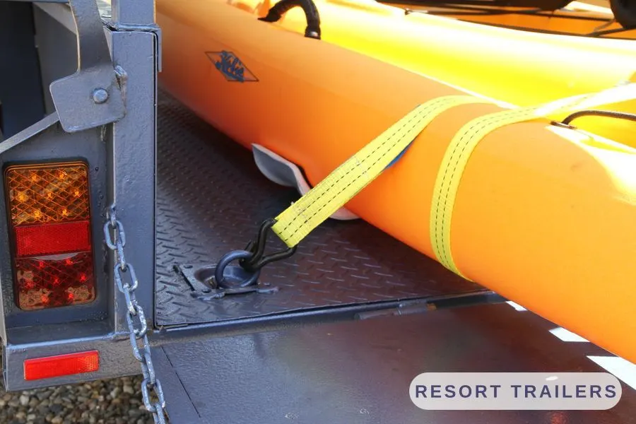 Kayaks strapped to tie-down points on the checker-plate deck — built by Resort Trailers