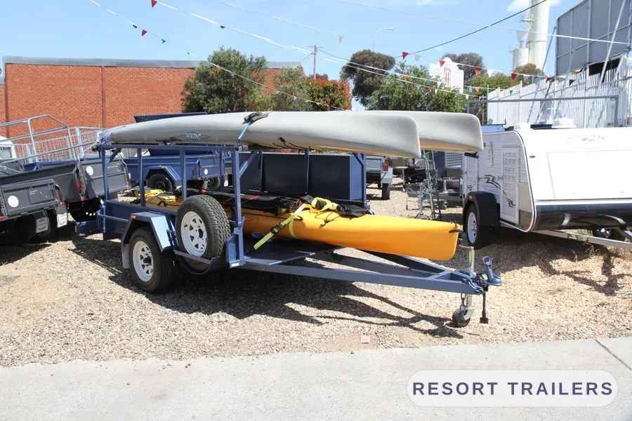 Two kayaks on top and two more on the deck, ready to tow — built by Resort Trailers